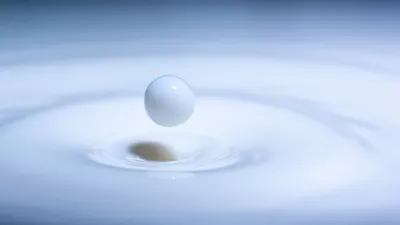 Dobras suaves de tecido branco e creme com uma gota de leite captada em luz quente e difusa, textura abstrata sem pessoas