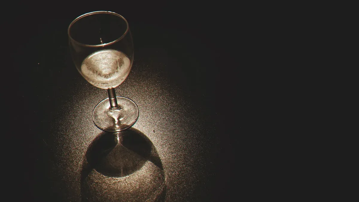 Três taças de champanhe próximas sobre uma mesa escura, em luz dourada e penumbra, sugerindo encontro íntimo entre várias pessoas