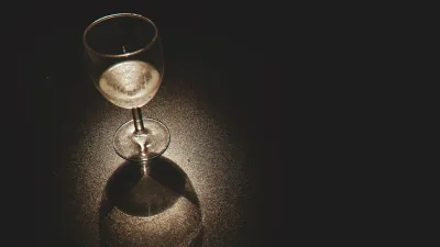 Três taças de champanhe próximas sobre uma mesa escura, em luz dourada e penumbra, sugerindo encontro íntimo entre várias pessoas